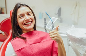 Happy patient in treatment chair, making thumbs-up gesture