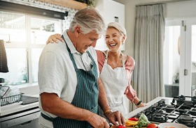 Healthy older couple preparing meal and laughing