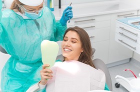 Happy dental patient holding mirror, admiring her new smile