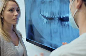 Dentist and concerned patient looking at X-ray