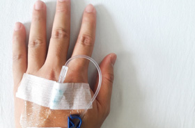 Close-up of patient’s hand with IV needle inserted