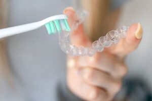 Person using soft toothbrush to clean Invisalign aligner