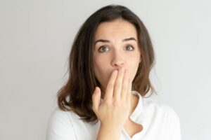 Woman in white blouse covering her mouth